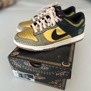 Nike women’s low dunk Familia in black khaki metallic gold.